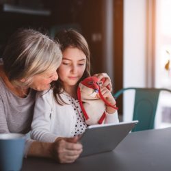 A small girl and her grandmother with tablet at home. Family and generations concept.